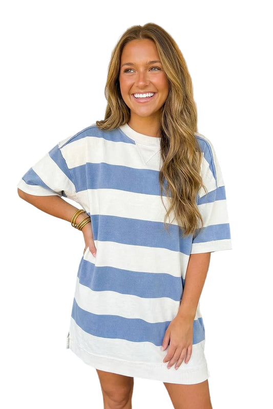 Woman wearing a blue and white striped dress standing in front of a door.