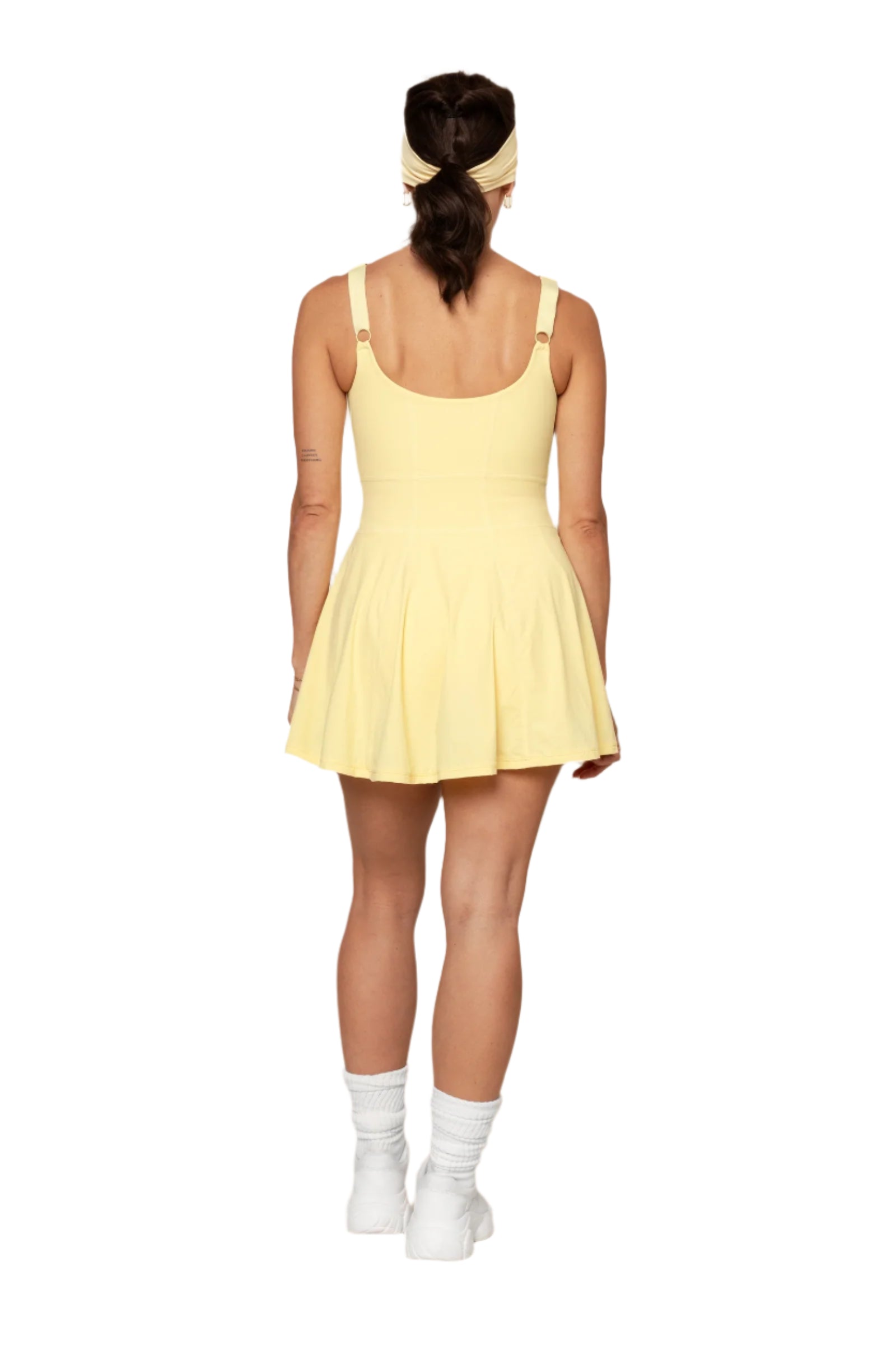 Person wearing a yellow athletic dress with a plain background
